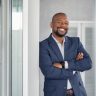 Mature cheerful african american executive businessman at workspace office. Portrait of smiling ceo at modern office workplace in suit looking at camera. Happy leader standing in front of company building.